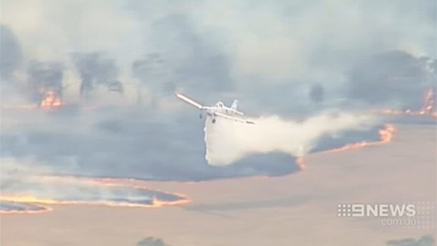 A firefighting plane dumps a load of water on a grassfire burning near Ararat in Victoria. (9NEWS)