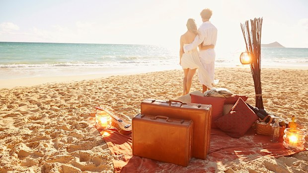 Caucasian couple with suitcases on tropical beach