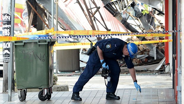 A NSW Police forensics photographer is seen at the scene of Thursday's deadly explosion in Rozelle. (AAP)