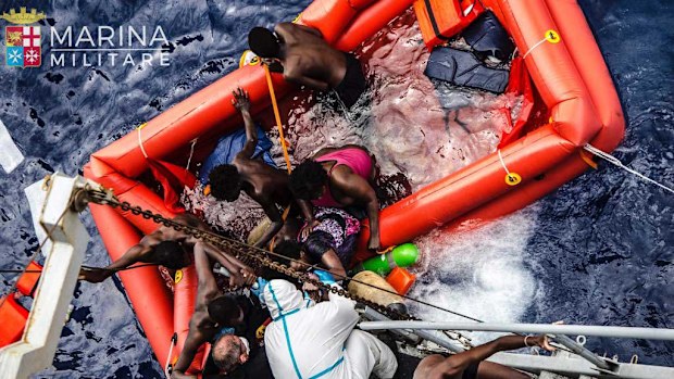 Rescuers help migrants to board the Italian Navy ship Vega, after the boat they were aboard sunk. The Italian navy says it has saved 135 migrants from a sinking boat and recovered 45 bodies in the Mediterranean. (AP)