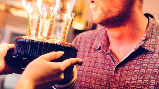 Woman holding cake for man at birthday celebration.