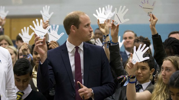 Britain's Prince William holds a cardboard hand with the names he wrote down of five people he would turn to in the event of bullying.
