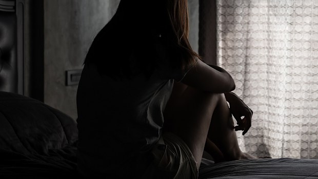 Sad woman sitting in the dark at window