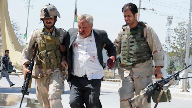 Members of the Afghan police forces help a man wounded when gunmen stormed the office of the Attorney General. (AAP)