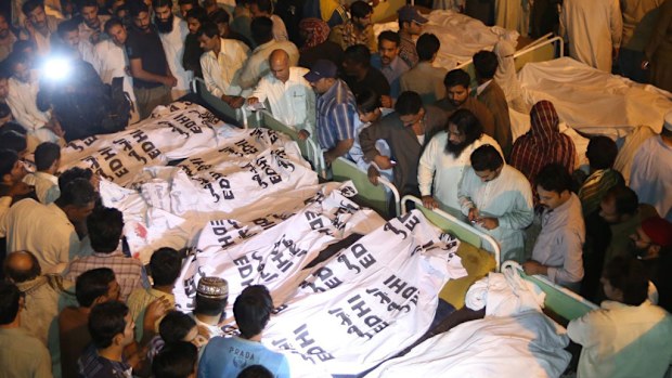 Locals crowd around the bodies of the victims of a suicide bomb attack. (AAP)