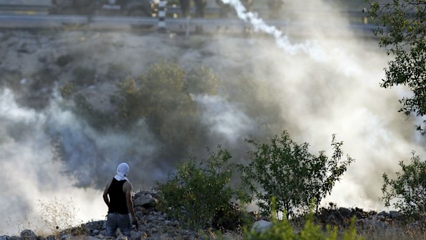 Israeli security forces stand looking at Palestinian protesters during clashes in the West Bank village of Silwad yesterday. (Getty Images)