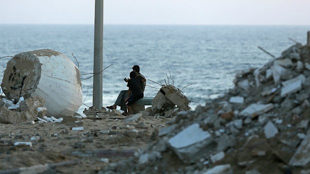 Palestinians sit between rubble at the beach of Gaza City during a 72-hour truce, 05 August 2014. (AAP)