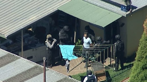 Police detain a man who emerged from the backyard shed at the home in Sydney's Guildford. (9NEWS)
