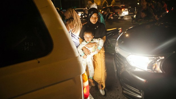 An Indonesian woman carries her child while walking to an open space in Pedang.