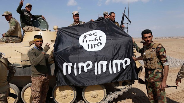 Iraqi government forces hold an ISIS group flag. (AFP)