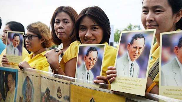 Women pose for cameras whilst holding images of Thailand's King Bhumibol Adulyadej during the commemoration of the 70th anniversary of his reign in Bangkok on June 9, 2016. (AFP)