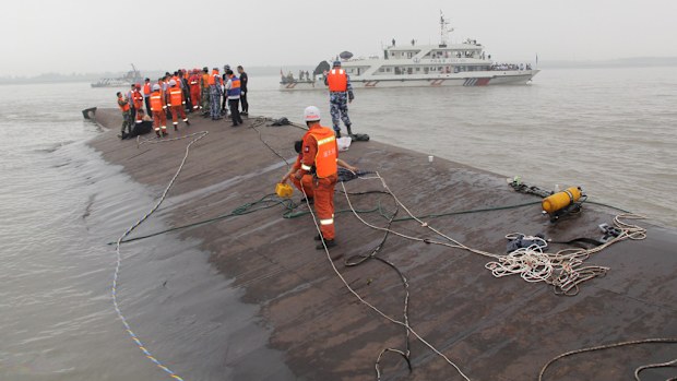 Rescue workers on the hull of the swamped ship. (Getty Images)