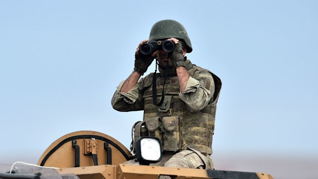 A Turkish soldier looks through a pair of binoculars towards the Syrian town of Kobane. (Getty Images)