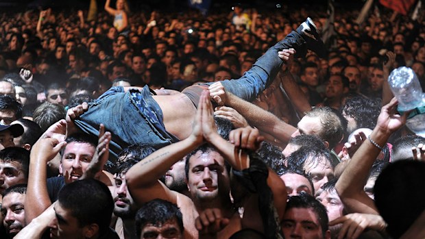 A fan who was dancing in the mosh pit at the Indio Solari show is lifted to remove him from the area, toward security. (AAP)