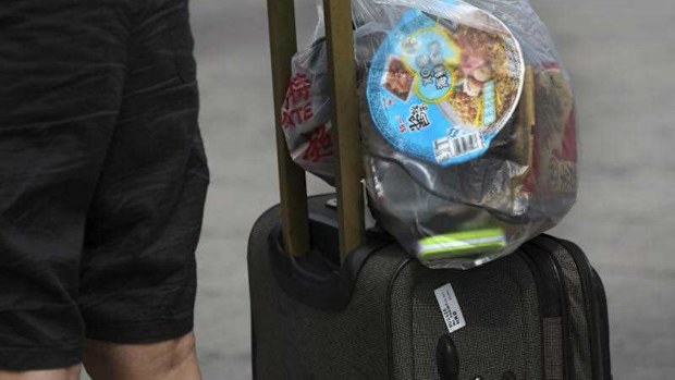 An airport passenger carries luggage through a terminal. (AAP)