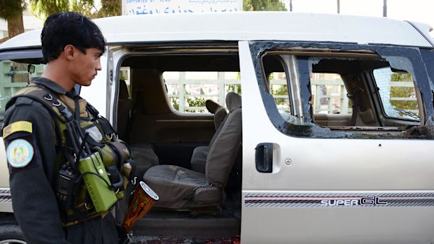 An Afghan policeman inspects a damaged vehicle in Kandahar on December 17, 2016, in which five female airport workers were killed. (AFP)