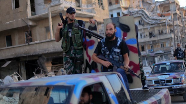 Armed rebel fighters from the Islamic Front drive their pickups past buildings which were damaged during fighting between Syrian government forces and opposition forces today in the northern city of Aleppo. (Picture: AHMED DEEB/AFP/Getty Images)