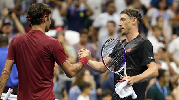 John Millman de Australia saluda a Roger Federer de Suiza en la red.
