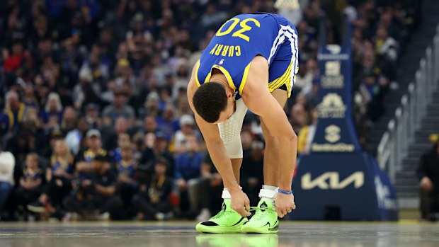 Stephen Curry of the Golden State Warriors ties his Under Armour sneakers.