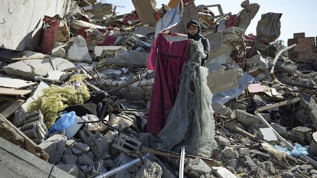 Nour Abu Al Zamar salvage items from under the rubble of her destroyed family home, in Rafah, southern Gaza Strip, Tuesday, Jan. 21, 2025, days after the ceasefire deal between Israel and Hamas came into effect. (AP Photo/Abdel Kareem Hana)