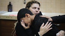 Raweah Safiya consoles one of her children as he cries over the death of his brother, Nabil Safiya, at the family's home in Kafr Yasif, northern Israel, on Sunday, January 18, 2026. 