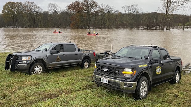 Patrol vehicles and rescue boats are from rescue efforts on a swollen river in Manes, Missouri.