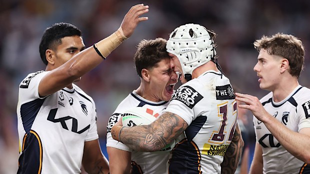 Jordan Riki of the Broncos celebrates with teammates after scoring a try.