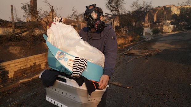 Josh Lederer wears a mask to protect him from fumes as he retrieves his children's clothes from his fire-ravaged property in the aftermath of the Palisades Fire in the Pacific Palisades neighborhood of Los Angeles.
