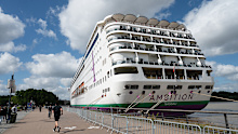 People walk past the British cruise ship Ambition, after French authorities ordered 1700 passengers and crew to stay on board due to a gastrointestinal illness outbreak, in Bordeaux, south-western France, on Wednesday, May 13, 2026.