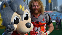 Willem Britz of Sunwolves poses for a photograph with team mascot WOLVY.