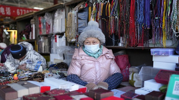 A senior woman waits for customers at a market in Beijing