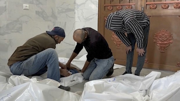 Family members unzips a body bag of children killed by by Israeli airstrikes in the morgue in the city of Khan Younis, southern Gaza Strip, Friday, Oct. 25, 2024. (AP Photo)