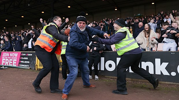 Los azafatos intentan impedir que un aficionado de Port Vale invada el campo durante el partido contra el Sunderland.