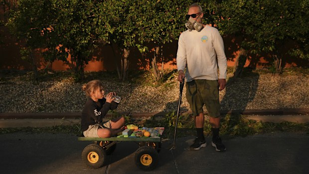 FILE - Resident Pauly Harter, right, pulls his son Gavin on a cart during a walk Friday, Jan. 10, 2025, in Altadena, Calif. (AP Photo/Jae C. Hong, File)