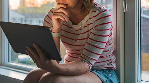 Woman sitting at home on computer sad