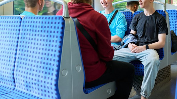 Young male friends sitting inside the train, talking and laughing together. Friendship, youth, guys aged 18-20 years, rail transport, passenger traffic