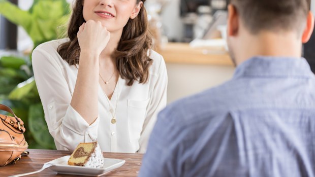 Young woman makes a disinterested face while on a date in a coffee shop. 