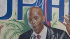 An ambulance carrying the body of Haiti’s President Jovenel Moise drives past a mural featuring him near the leader’s residence where he was killed by gunmen.