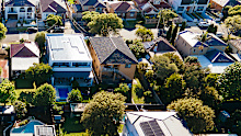 Aerial photograph showcasing a vibrant suburban neighborhood filled with various houses, gardens, and trees under bright daylight.