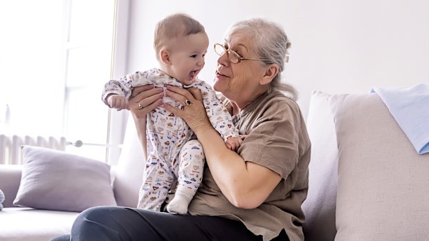 Grandmother holding little grandson in the room at home. 