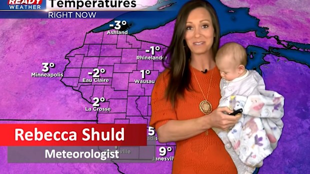 Meteorologist from the US does live cross with baby in hand. 
