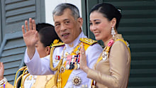 King Maha Vajiralongkorn and Queen Suthida wave to an audience from the balcony of the palace. (AP/AAP)