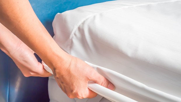 Woman is putting the bedding cover or mattress pad on the bed or putting off for cleaning process.