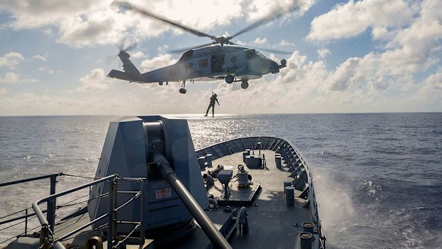 An MH-60R Seahawk from HMAS Toowoomba conducts a PAX transfer from the forecastle of the ship while the ship sails through the Philippines Sea.