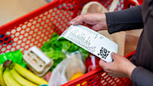 Close up of unrecognizable customer checking her receipt after purchasing groceries in the supermarket - Home shopping concepts