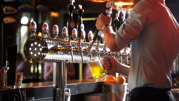 Barista in the pub pouring beer drink into glass for the customer.