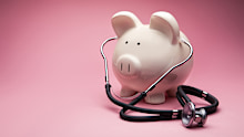 This is a photo of a large white piggy bank on a pink background. This is a concept photo related to finance and the medical hospital industry,