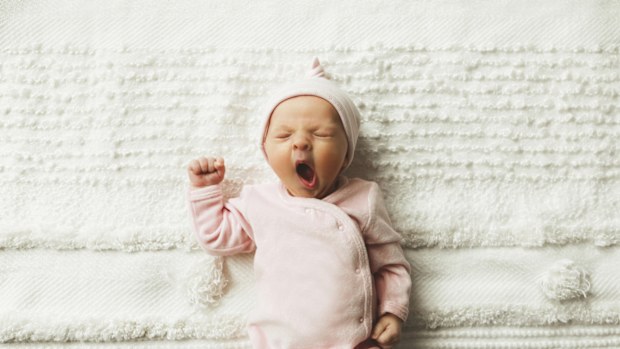 A close-up of an adorable baby girl, 4.5 weeks old, yawning. 