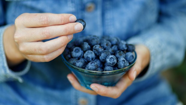 Woman eating ripe blueberries, healthy berries.