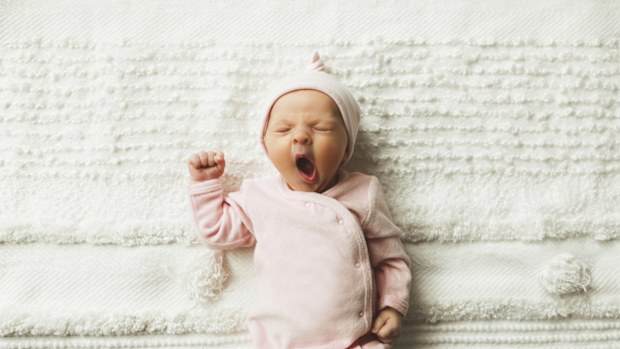 A close-up of an adorable baby girl, 4.5 weeks old, yawning. 